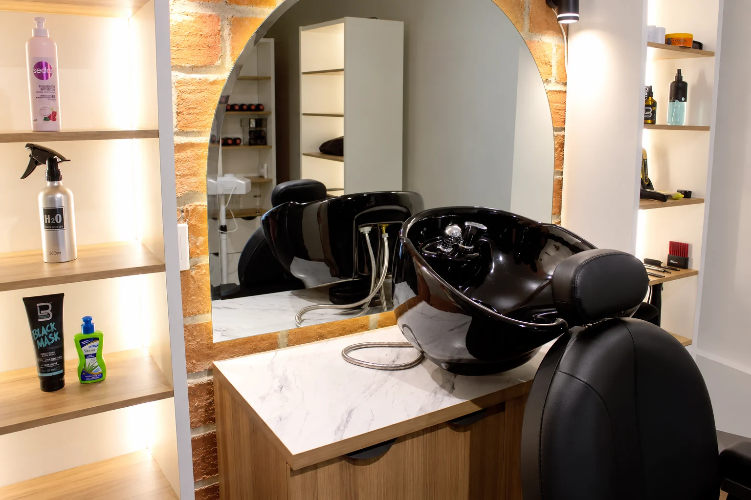 Área de lavado de la barbería Medellín Hair Solutions en León, con pared de ladrillo y espejo